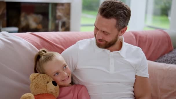 Vater schaut entzückende Tochter auf Sofa an. Glücklicher Mann im Gespräch mit kleinem Mädchen — Stockvideo