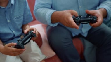 Erkek ve çocuk elleri bilgisayar oyunu oynuyor. Büyükbaba ve torun joystick kullanıyor.