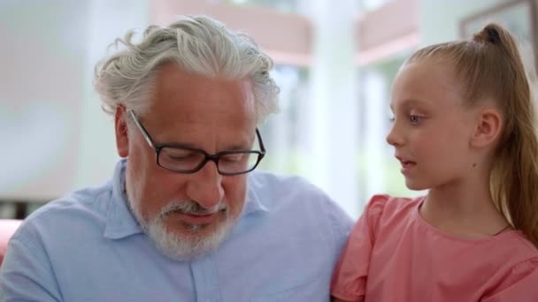 A lány nagyapa ölében ül. A nagyszülő az unokáját tanítja számolni. — Stock videók