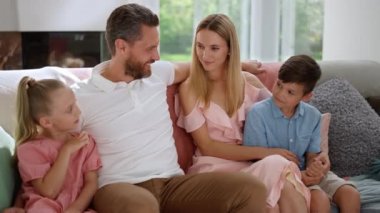 Çekici anne ve baba çocuklarına sarılıyor. Mutlu ebeveynler çocuklara bakıyor.
