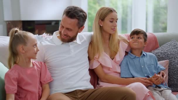Familie zit op de bank in de woonkamer. Vrouw en man in gesprek met kinderen — Stockvideo