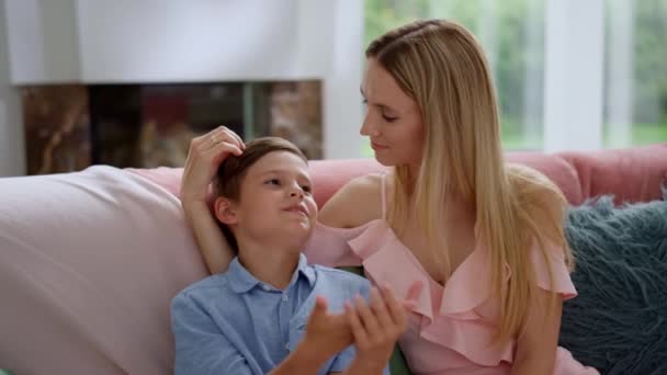 Mutter und Sohn reden zusammen im Wohnzimmer. Vorsichtige Frau berührt Knabenhaare — Stockvideo