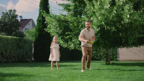 Ευτυχισμένος πατέρας και κόρη παίζουν με ιπτάμενο δίσκο στην πίσω αυλή — Αρχείο Βίντεο
