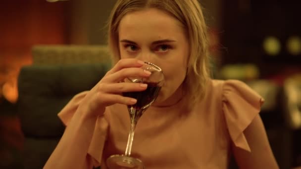 Женщина пьет вино за обеденным столом. Красивая девушка кладет бокал вина на стол — стоковое видео
