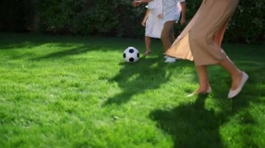 Çocuklar ve ebeveynler futbol oynuyor. Aile futbol topuyla koşuyor
