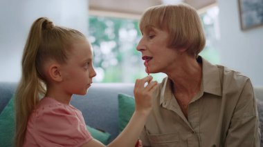Büyükannem için makyaj yapan bir kız. Rujla oynayan kadın ve torun.