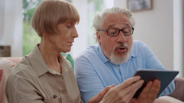 Mies katselee tabletin näytön naisen kanssa.Isovanhemmat käyttävät tabletin videopuhelu — kuvapankkivalokuva