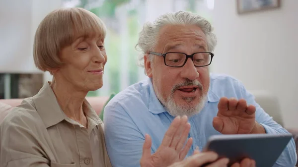 Lykkelig eldre mann og kvinne som vifter med hendene under videooppringningen – stockfoto