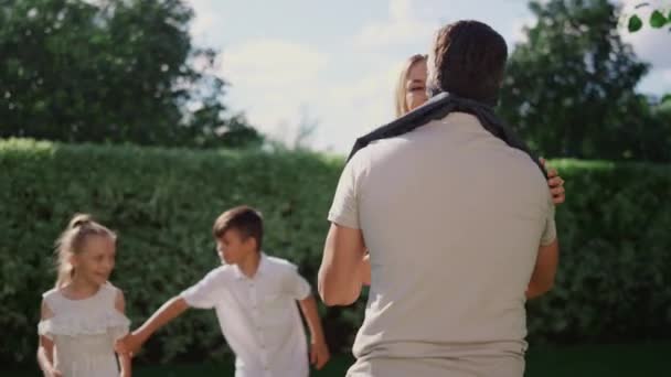 Familjen leker blind man buff i trädgården. Lycklig far i blind fånga pojke — Stockvideo