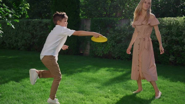 Preteen boy wirft fliegende Scheibe auf Schwester im Park. Nettes Mädchen, das Scheibe fängt — Stockfoto