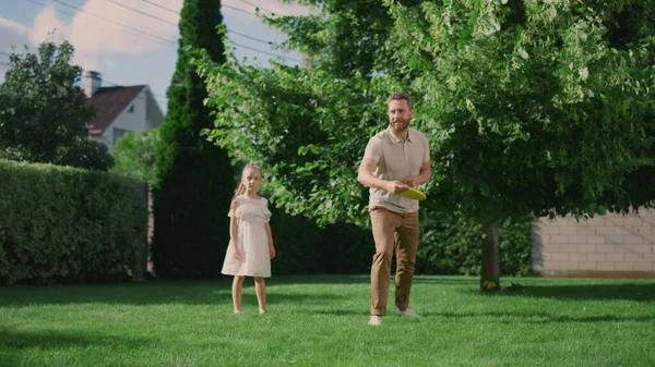 Glad far och dotter leker med flygande skiva på bakgården — Stockfoto