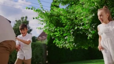 Park 'ta kör adamı oynayan bir aile. Çocuklar aileleriyle arka bahçede koşuyor.