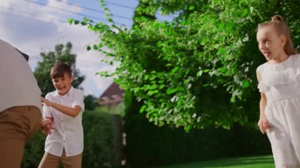 Park 'ta kör adamı oynayan bir aile. Çocuklar aileleriyle arka bahçede koşuyor. — Stok video