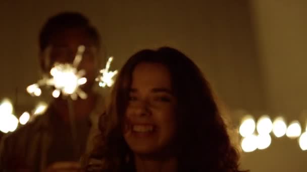 男人和女孩手握火花跳舞。玩世不恭的女孩在镜头前笑 — 图库视频影像