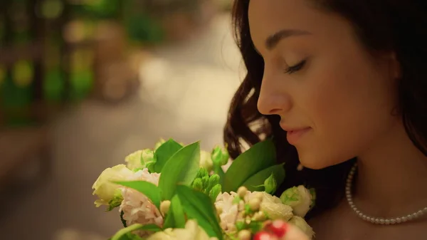 Sposa bruna posa con fiori in giardino. Donna che annusa fiori all'aperto — Foto Stock