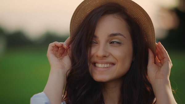 Smiling woman wearing straw hat outdoors. Portrait of joyful lady in park