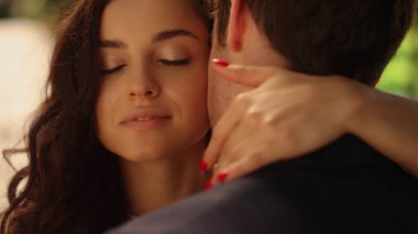 Çekici gelin bahçede damada sarılıyor. Park yerinde bekleyen çift.