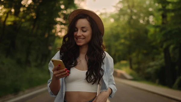 Menina bonita andando ao ar livre. Mulher sorridente mensagem de texto no telefone no parque — Fotografia de Stock