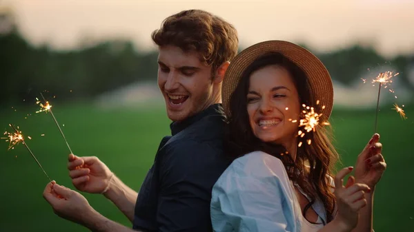 Casal atraente em movimento com luzes no parque. cara e menina posando com sparklers — Fotografia de Stock