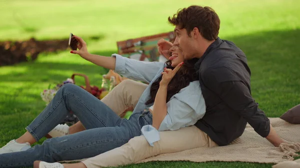 Menina brincalhão e cara se divertindo no parque. Bonito casal tomando selfie ao ar livre — Fotografia de Stock