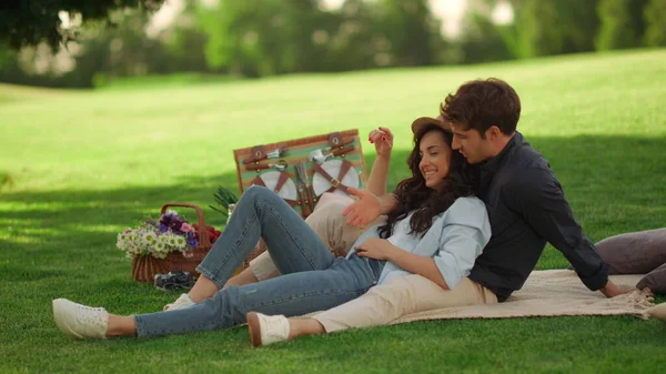Mladý muž a žena se venku smějí. Dívka a chlap sedí na dece v parku — Stock fotografie