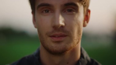 Gün batımında kameraya bakan yakışıklı bir adam. Neşeli model çocuk.