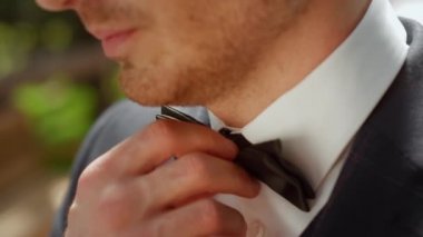 Neşeli damat kemer altında düğüne hazırlanıyor. Bahçede gülümseyen adam