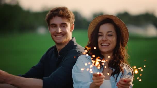 행복 한 커플이 초원에서 더듬거리는 불빛을 가지고 노는 모습. 야외에서 파티를 즐기는 부부 — 비디오