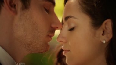 Seksi yeni evliler parkta yüzlerine dokunuyor. Kadın ve erkek açık havada duygularını gösteriyor.