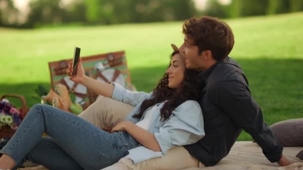 Счастливая девушка и парень делают видеозвонок в парке. Пара приветствий по телефону — стоковое видео