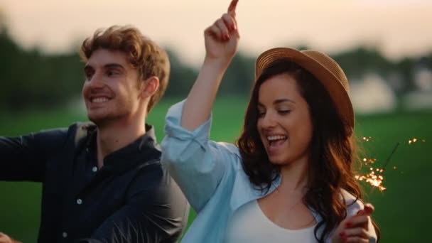 Fröhliches Paar tanzt mit Wunderkerzen im Sommerpark. Aufgeregte Menschen genießen Party — Stockvideo
