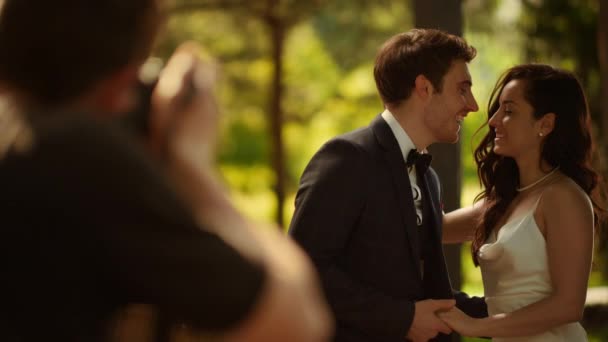 Pareja feliz posando en sesión de fotos. Novia y novio mostrando anillos al aire libre — Vídeos de Stock