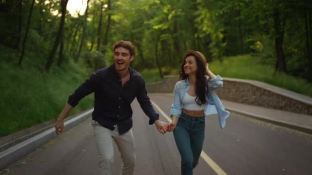 아름다운 소녀와 남자가 공원에서 뛰어 내린다. 밖에서 즐거운 시간을 보내는 젊은 부부 — 비디오
