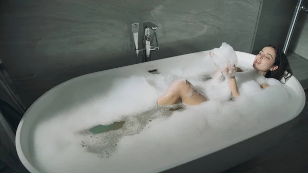 Jolie fille couchée dans le bain à l'intérieur. Douce dame appréciant la baignoire à bulles. — Photo