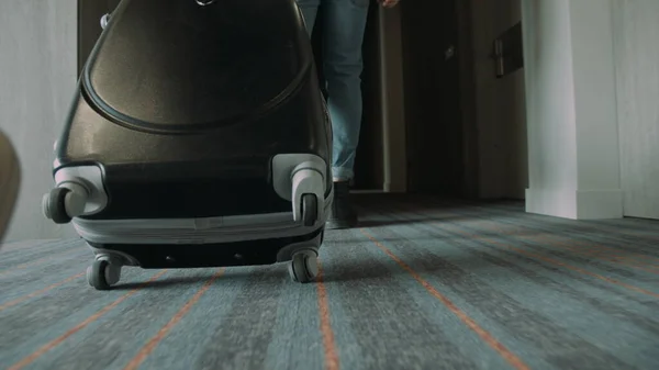 荷物を背負ったまま廊下を歩くブーツ姿の男性の足。スーツケースを持ってる男. — ストック写真