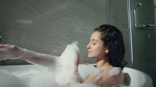 Mulher bonito brincando com espuma de banho no banheiro do hotel. Menina sexy deitado no banho. — Fotografia de Stock