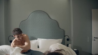 Gülümseyen çift lüks otel odasında eğleniyor. Yastıklarla savaşan seksi çift.