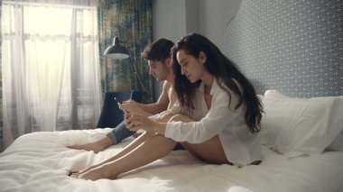 İçeride akıllı telefon kullanan sakin bir çift. Telefon ekranlarına dokunan ciddi bir çift.