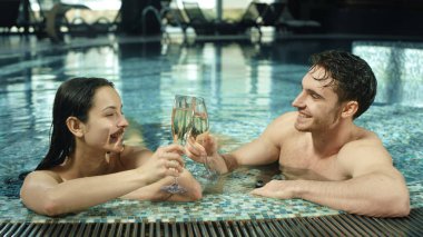 Spa havuzunda kadeh tokuşturan güzel bir çift. Kadın ve erkek jakuzide flört ediyorlar.