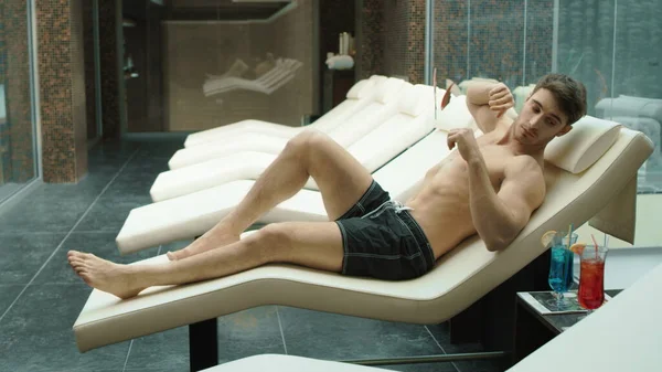 Een atleet die cocktail drinkt in een kuuroord. Sexy man ontspannen in wellness centrum. — Stockfoto