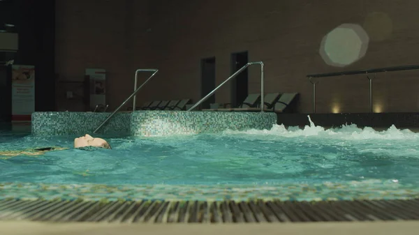 Bella donna nuotare sul retro nella piscina termale. Bella ragazza che si rilassa nella vasca idromassaggio — Foto Stock