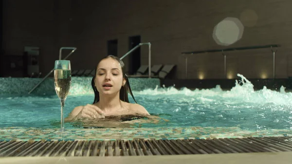 Sinnliche Mädchen entspannen mit Wein im Wellnessbereich. Hübsche Frau kommt aus Wasserbecken. — Stockfoto