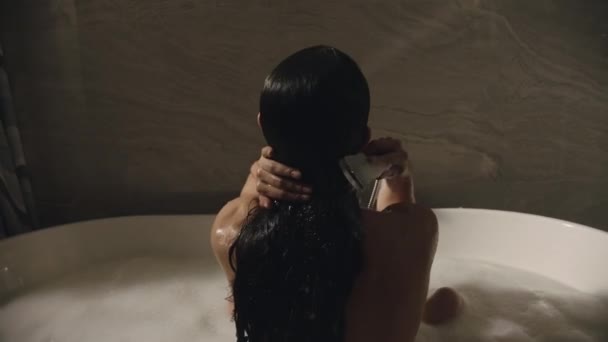 Szczupła kobieta siedząca w wannie na poddaszu. Dziewczyna mycie włosów z prysznicem — Wideo stockowe
