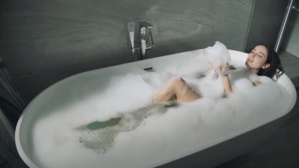 Nettes Mädchen liegt im Bad drinnen. Süße Dame genießt Schaumbad. — Stockvideo