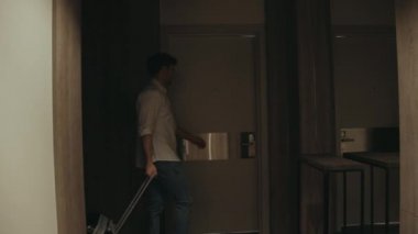 Bavulu olan yakışıklı bir adam otel odasını açıyor. Lüks daireye gelen adam.