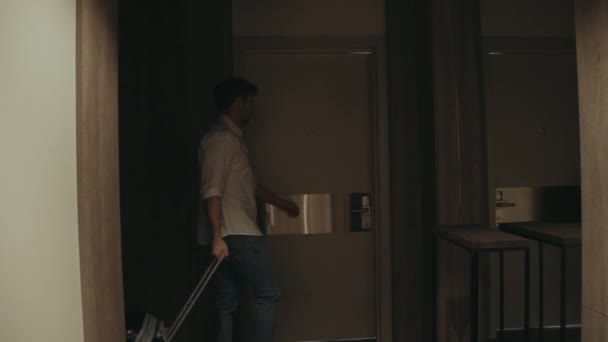 Симпатичный парень с чемоданом, открывающим дверь гостиничного номера. Человек приходит в элитную квартиру. — стоковое видео