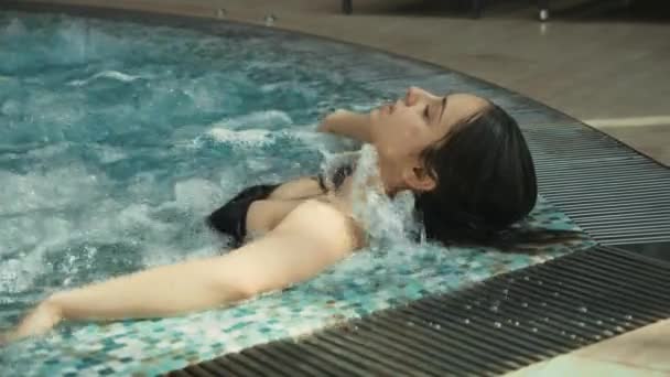 Krásná dívka si užívá hydroterapie v lázních. Nádherná žena relaxující ve vířivce. — Stock video