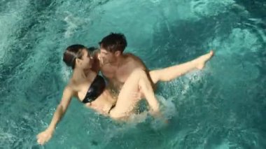Havuzda kucaklaşan romantik bir çift. Termal havuzda kadını tutan adam