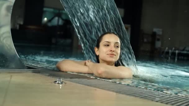 Gelukkig meisje dat lacht voor iemand in het zwembad. Mooie vrouw rustend in spa — Stockvideo