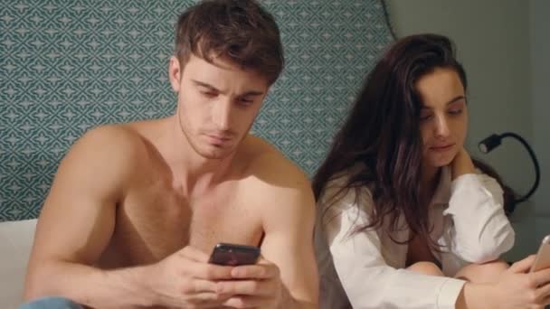 Focused couple scrolling smartphones bed. Serious couple looking phone screens — Stock Video